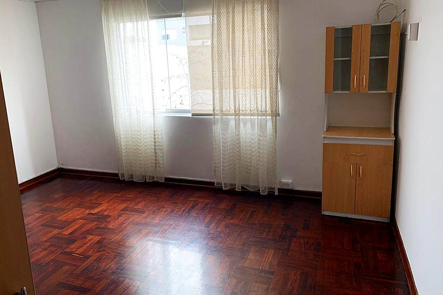 Habitación alquilada en La Aurora, Miraflores, con piso de parquet y ventana a la calle